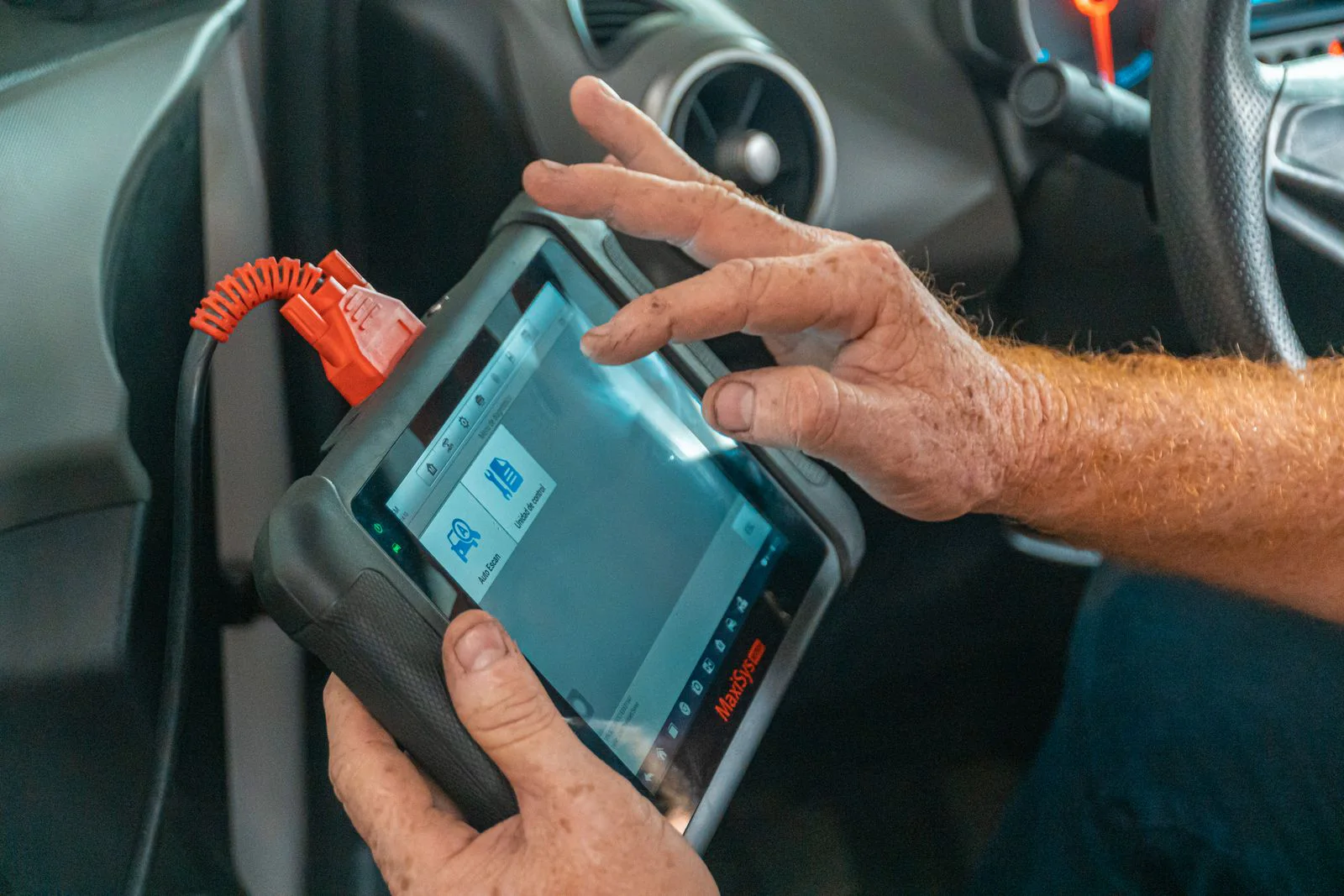 Araç içinde elektronik diagnostik cihazıyla kontrol yapan teknisyen